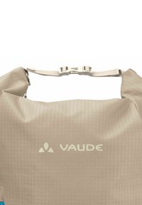 Beige wasserdichte Tasche mit strukturierter Oberfläche, ausgestattet mit einer silbernen Schnalle und dem VAUDE-Logo in Weiß. Kompaktes Design, geeignet für verschiedene Anwendungen.