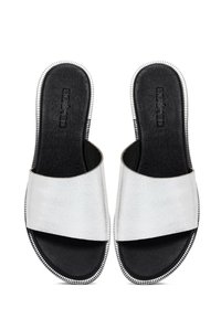 Witte leren slide-sandalen met een gestructureerde afwerking, open teen en een zwarte binnenzool. Beschikt over metallic afwerking langs de buitenrand.