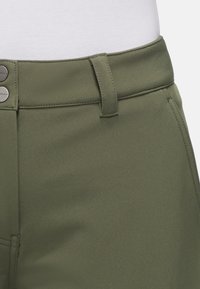 Pantalon en tissu vert avec une texture lisse, présentant un devant plat, deux boutons en métal à la taille et une conception standard de passants de ceinture.