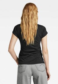 Black short-sleeve t-shirt made of soft material; fitted design with a rounded neckline, paired with light grey high-waisted jeans.