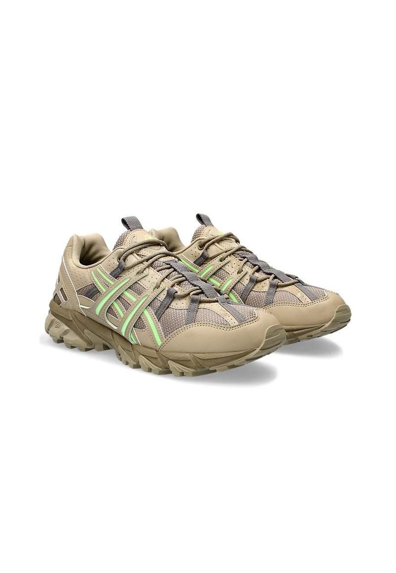 Par de zapatillas de trail running de malla beige y gris con acentos en verde neón y suelas rugosas, mostradas desde un ángulo frontal de tres cuartos.