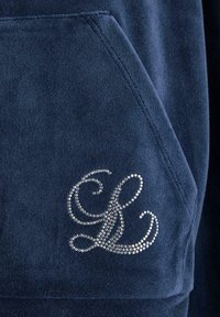 Hoodie en polaire bleu marine avec une poche devant ; présente un "L" en cursive orné de cristaux sur la poche. Texture douce, design décontracté.