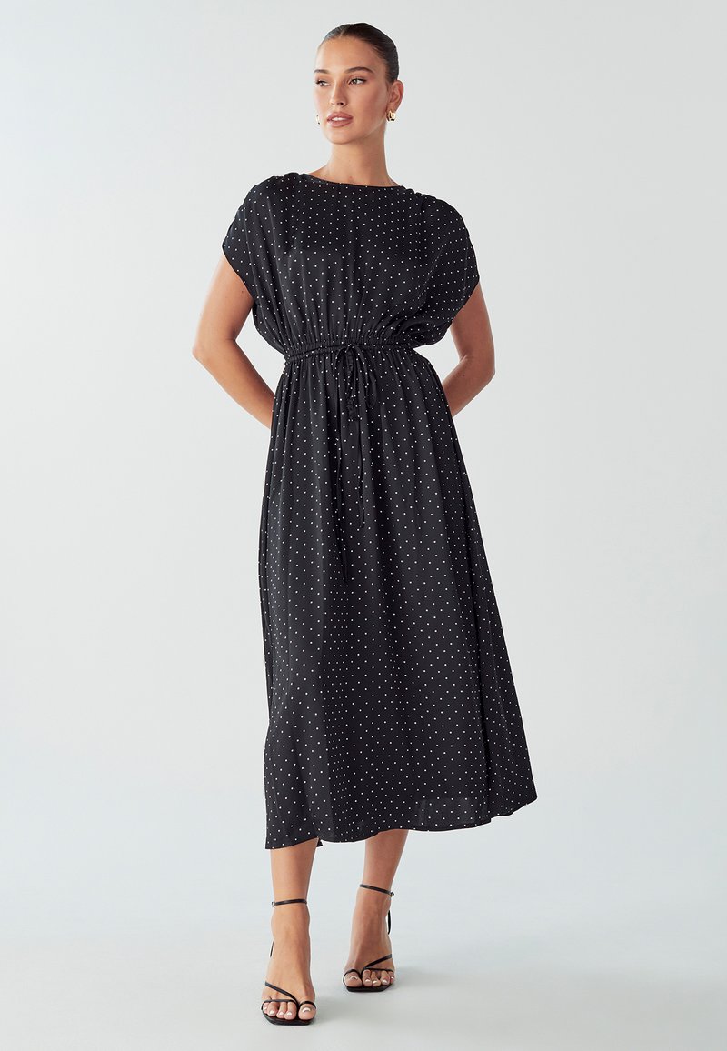 Black polka dot midi dress with short sleeves, cinched waist, and smooth fabric. Features a loose fit and ankle-length design.