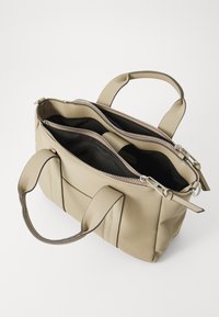 Beige leather handbag with dual zippered compartments, featuring sturdy handles and a sleek design, lined in black fabric.