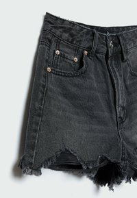 Schwarze Jeansshorts mit ausgefransten Säumen, Vordertaschen und Kupfernieten, gezeigt vor einem schlichten hellen Hintergrund.