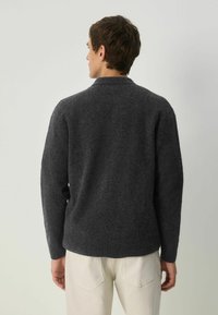 Pulover tricotat de culoare gri închis, cu o textură moale, manșete și tiv cu bande. Designul include un guler clasic și o croială lejeră.