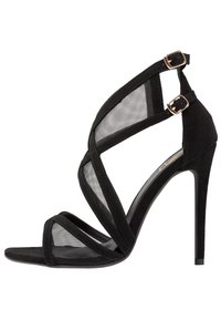 Mustat korkeakorkoiset sandaalit, joissa on mokkanahkaa, verkko-yksityiskohtia ja ristikkäin meneviä hihnoja. Varpaanosa on terävä ja korko on hoikka stiletto.