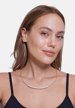 Collier en or mettant en valeur une rangée de petites perles blanches intégrées dans un design métallique rond simple et épuré.