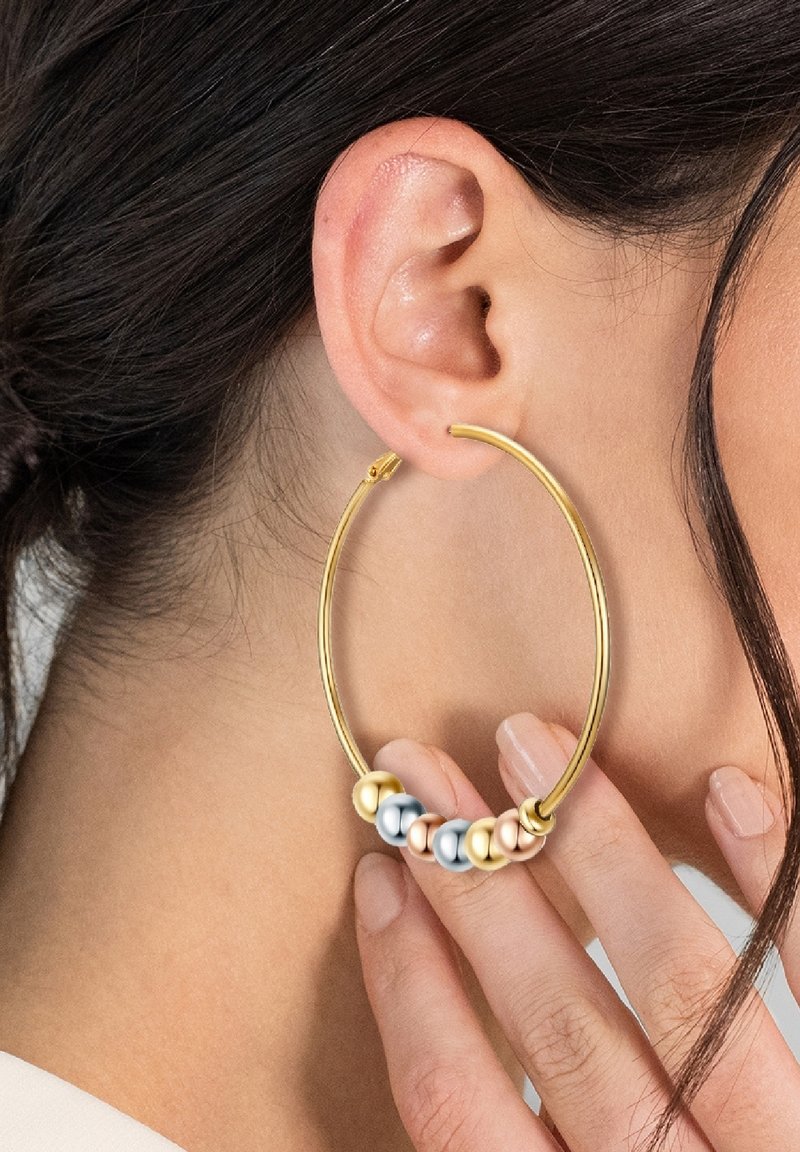 Zelta gredzenveida auss gredzens ar daudzkrāsainu pērļu grupu—baltām, sudraba un rozā zelta—tuvojoties apakšai. Gluda tekstūra, apaļa forma.