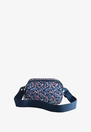 Tumsnēdzilā plecu soma ar regulējamu siksnu, dekorēta ar mazām rozā, baltām un zaļām ziedu rakstām un priekšpusē ar rāvējslēdzēju.