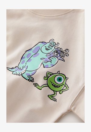 Beige fleecepaita, jossa värikkäät sarjakuvamaiset kuvat sinisestä monsterista, jolla on violetteja täpliä, ja vihreästä pyöreästä monsterista, molemmat hymyilevät.