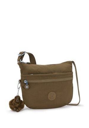 Bruine stoffen crossbodytas met een voorzak met rits, verstelbare band en een aangehechte zachte apensleutelhanger op een witte achtergrond.