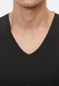 Zwarte V-hals T-shirt van zacht materiaal, met een gladde textuur en een strakke, eenvoudige snit zonder patronen of accenten.