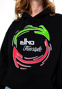 Schwarzer Hoodie mit einer Vordergrafik, die rote und grüne kreisförmige Pfeile zeigt. "elho" und "Freestyle" Text in Weiß. Weicher Stoff.