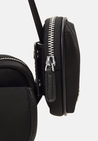 Borsa a tracolla nera in nylon con un design compatto e rettangolare, dotata di chiusura con zip e dettagli in metallo argentato.