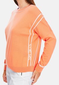 Pull orange avec rayures accent blanches, col et poignets en maille côtelée, coupe décontractée, fabriqué en tissu doux et respirant.