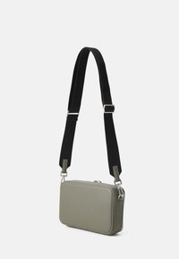 Rektangulær crossbody-veske i olivengrønn kunstskinn, med justerbar svart stropp og sølvfargede detaljer. Glatt tekstur med sømkanter.