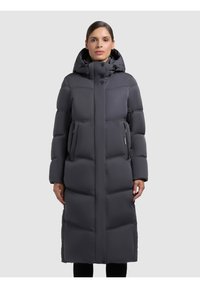Dlouhý, polstrovaný šedý péřový kabát s kapucí, který má dvě boční kapsy na zip a rovný střih. Texturované prošívané panely po celé délce.