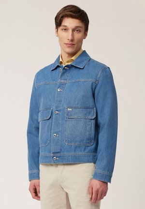 Lichtblauwe spijkerjack met een knoopsluiting aan de voorkant, twee borstzakken en een platte kraag. Gladde textuur en casual ontwerp.