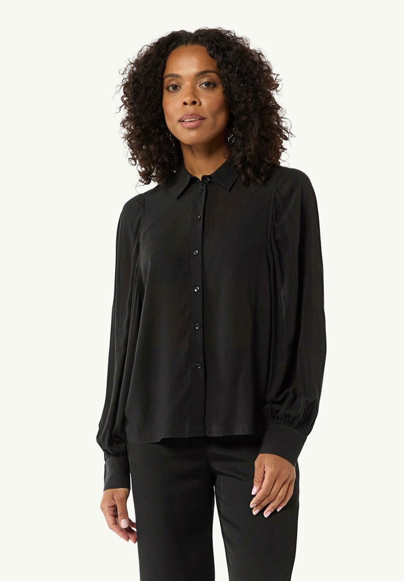 Black long-sleeve blouse in silky fabric with a button-down front, pointed collar, puffed sleeves, and fitted cuffs.