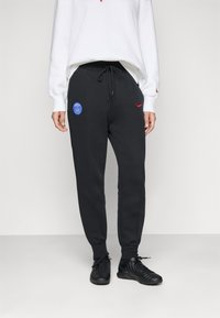 Sorte joggebukser med snor i livet, med en blå Paris Saint-Germain-logo og en rød Nike-svosh på venstre hofte.