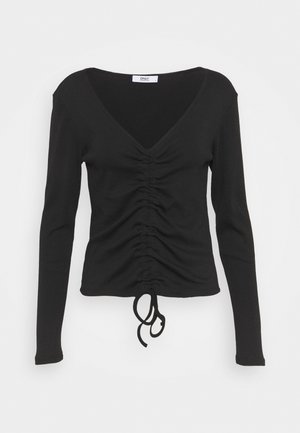 Haut noir à manches longues avec col en V, devant froncé et lien ajustable à l'ourlet, style ajusté.