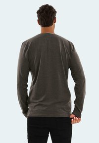 Graues Langarmshirt aus weichem Stoff, mit rundem Ausschnitt und normaler Passform. Es gibt keine sichtbaren Muster oder Akzente.