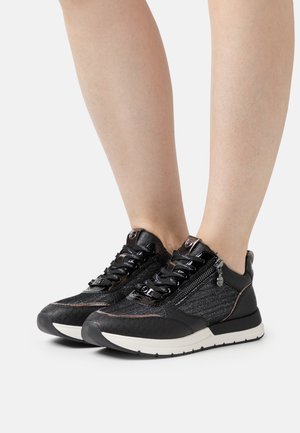Baskets de sport noires avec une tige texturée, des accents brillants, un laçage et une fermeture éclair sur le côté. Semelle blanche au design sportif.
