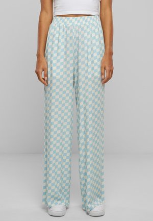 Weit geschnittene Hosen mit hellblauem und weißem Schachbrettmuster, getragen mit weißen Sneakers und einem cropped weißen Top.