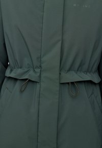 Dunkelgrüne Jacke mit einer weichen, matten Oberfläche. Verfügt über eine geraffte Taille mit Zugbändern und einer verdeckten Vorderleiste. Einfaches Design, keine Verzierungen.