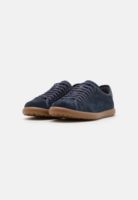 Sneaker in suede navy con forma arrotondata, suola in gomma beige e lacci coordinati. Texture liscia con dettagli di cucitura minimi.