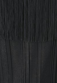 Svart plisserad tyg med vertikala ränder och texturerade fransar på toppen, vilket skapar ett lager på lager-utseende.