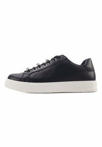 Black leather sneakers with a textured white sole, round toe, and metallic lace eyelets. Side panels feature stitched accents for added design.
