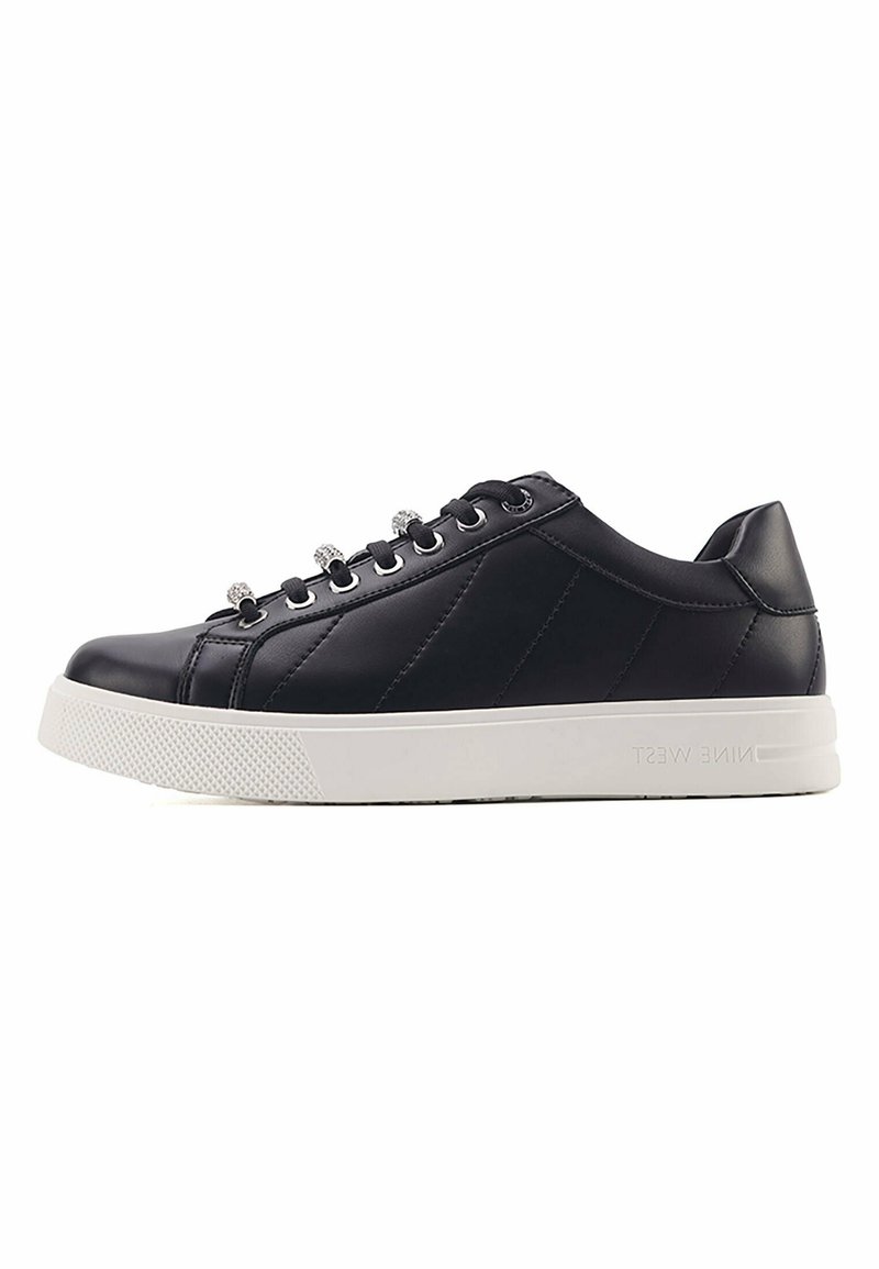 Black leather sneakers with a textured white sole, round toe, and metallic lace eyelets. Side panels feature stitched accents for added design.