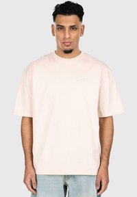 Kurze Ärmel, hellrosa T-Shirt aus Baumwolle mit Rundhalsausschnitt und dezent gesticktem Logo auf der linken Brust.