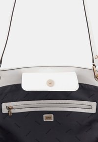 Sac à main blanc et gris avec une fermeture à pression magnétique, doublure intérieure noire, une poche zippée et quincaillerie dorée. Logo affiché à l'intérieur.