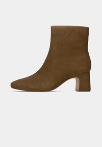Bottine en daim marron avec talon bloc et bout arrondi, vue de profil sur un fond clair uni.