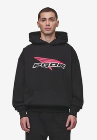Felpa nera con cappuccio realizzata in tessuto morbido, presenta una tasca frontale e un grande logo grafico in bianco e rosa. Vestibilità ampia con cappuccio e polsini a costine.