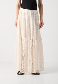 Maxikleid aus Spitze in Creme, mit einem gestuften Design und strukturierten Mustern, elastischem Taillenbund und einem fließenden Schnitt.
