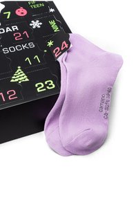 Lila Knöchelsocken aus weichem Material mit gerippter Textur, neben einem schwarzen Adventskalender mit bunten Zahlen und Details präsentiert.