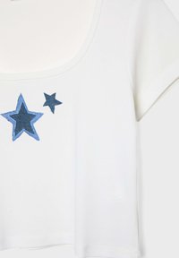 Hvid bomulds T-shirt med bred halsudskæring. Har blå broderede stjernemotiver i forskellige størrelser på forsiden. Korte ærmer, afslappet pasform.