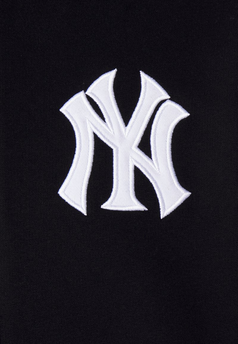 Black fabric features a prominently embroidered white "NY" logo, showcasing a bold, stylized design with pronounced curves and sharp edges.