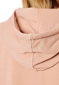 Sudadera de color rosa claro con una textura suave, cordón ajustable y una capucha redondeada con costuras visibles a lo largo de la unión.