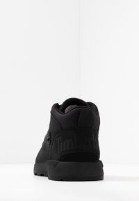 Schwarzer Timberland Sneaker aus Wildleder mit hohem Design, gepolstertem Knöchel, geprägtem Logo an der Ferse und Gummisohle.
