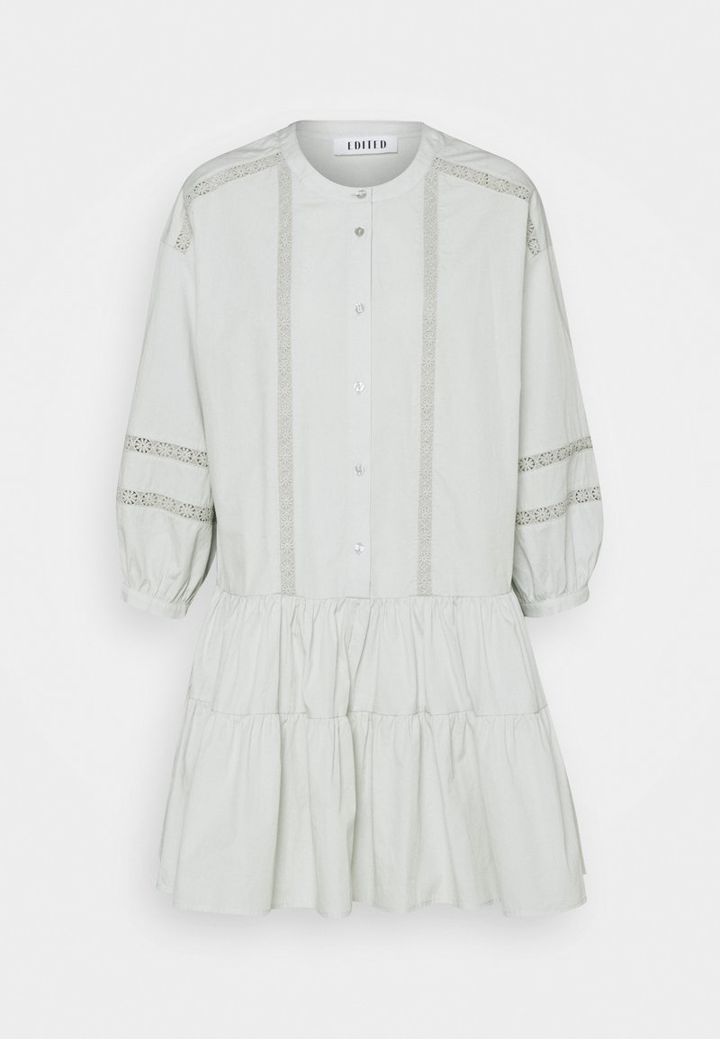 Jasnoszara bawełniana sukienka z guzikiem z przodu, okrągłym dekoltem, zdobionymi koronkowymi akcentami i warstwowym dołem z falbanami. Rękawy o długości trzech czwartych z bufkami.