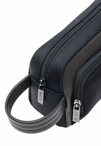 Czarna kieszeń na zamek błyskawiczny o teksturowanej powierzchni, skórzanym uchwycie i błyszczących metalowych elementach. Kompaktowy design z podwójnymi zamkami.