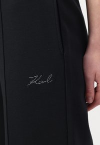 Schwarze Jogginghose mit weicher Textur, schmaler Passform und einem dezenten, silbernen, gestickten "Karl"-Logo an der Seite.