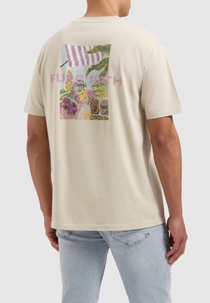 Beige katoenen t-shirt met een kleurrijke fruitmarkt graphic op de achterkant, met de tekst "Pure Path" boven het ontwerp. Korte mouwen, relaxte pasvorm.