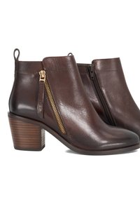 Bottines en cuir marron avec un bout arrondi, une fermeture à glissière sur le côté et un talon en bois empilé. La surface a une texture lisse et brillante.