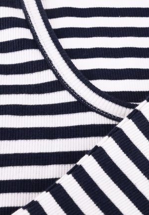 Close-up van marineblauw en wit geribbeld stof met horizontale strepen, een ronde halslijn en een detail van een omgeslagen mouw.